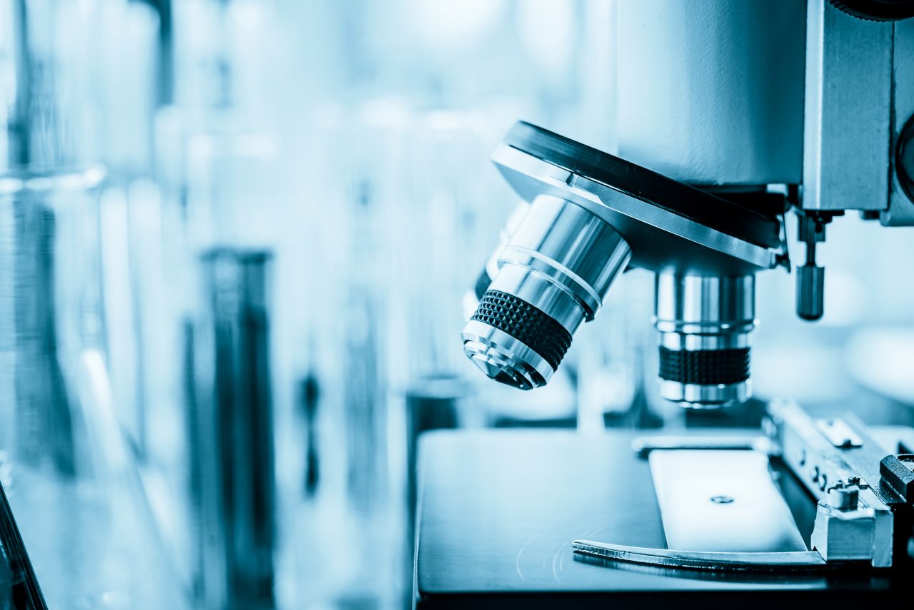 Microscope in microbiology lab with laboratory glassware background for